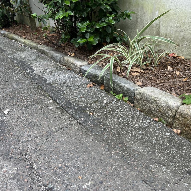 Application image for Granite - Reclaimed New England Cobblestones - Jumbo Edging. The image shows this product being used in a landscape curbing & edging application. The dominant color shown is gray.