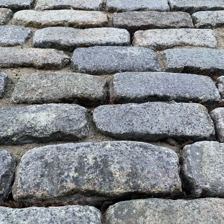 Best close-up image for Reclaimed New England Cobblestones - Jumbo Worn Top. The image shows this product being used in a driveway pavers application. The surface finish shown is a combination of weathered and worn. The dominant color shown is gray; with beige, blue, brown, green, purple, white and cream secondaries. Exhibits 
