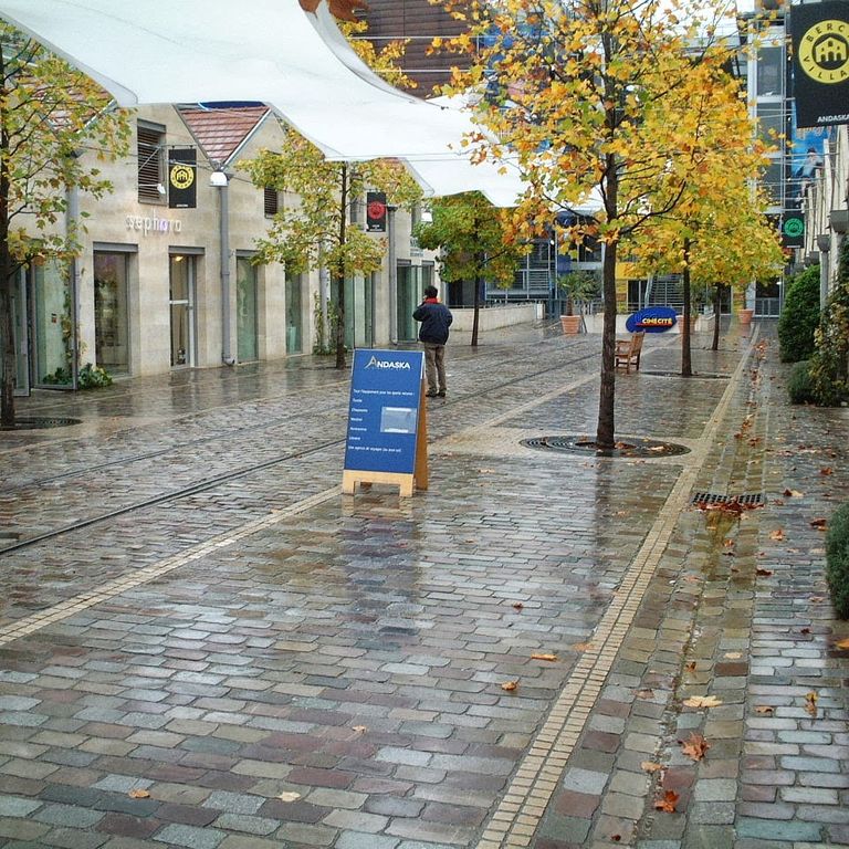 Feature image for Granite - Reclaimed Swedish Cobblestones - Flat Surface. The image shows this product being used in a public area application. The dominant color shown is gray; with beige, blue, brown, green, orange/rust, purple, white and tan secondaries. Speckled color pattern.