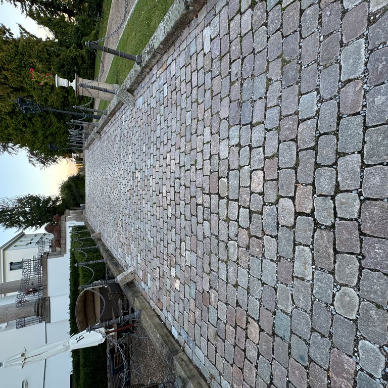 Application image for Granite - Reclaimed Swedish Cobblestones - Antique Surface. The image shows this product being used in a path pavers application. The surface finish shown is antiqued. Dominant colors shown are blue and gray. The color mix creates a cool feeling.