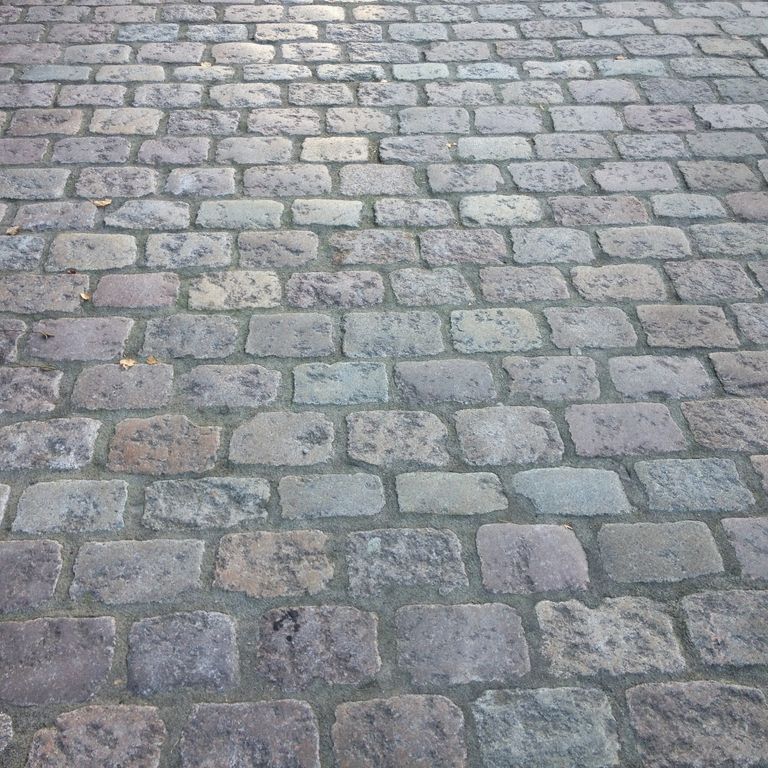 Application image for Reclaimed Swedish Granite Cobblestones - Worn Surface. The image shows this product being used in a driveway pavers application. The surface finish shown is . The dominant color shown is gray. The color mix creates a cool feeling.