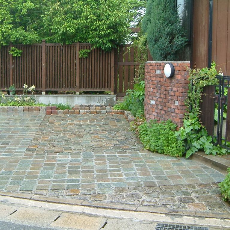 Application image for Porphyry - Reclaimed European Cobblestone - Square - Flat Surface. The image shows this product being used in a patio pavers application. The dominant color shown is gray; with beige, blue, brown, green, orange/rust, white and tan secondaries. The color mix creates a warm feeling. Speckled color pattern.