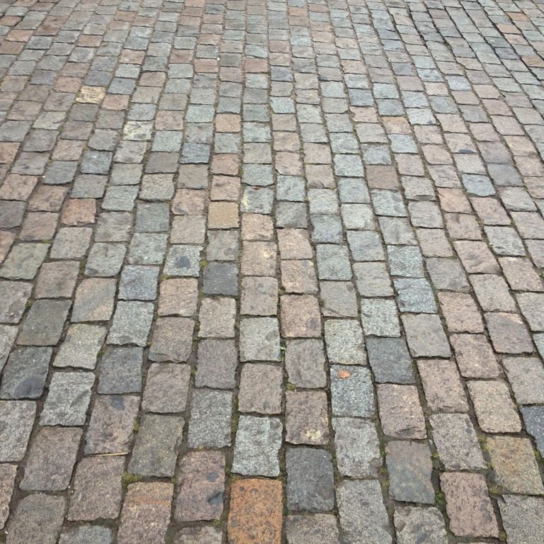 Application image for Reclaimed European Porphyry Cobblestones - Rectangle - Worn. The image shows this product being used in a driveway pavers application. The surface finish shown is . The dominant color shown is gray. The color mix creates a warm feeling.
