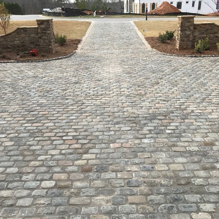 Application image for Reclaimed European Sandstone Cobblestones - Rectangle - Worn Surface. The image shows this product being used in a driveway pavers application. The surface finish shown is . The dominant color shown is gray. The color mix creates a warm feeling.