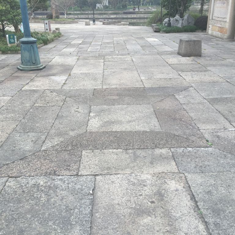 Close-up image for Reclaimed Porphyry Plank Pavers. The surface finishes shown are weathered and worn. The dominant color shown is gray; with beige, blue, pink and white secondaries. Exhibits 