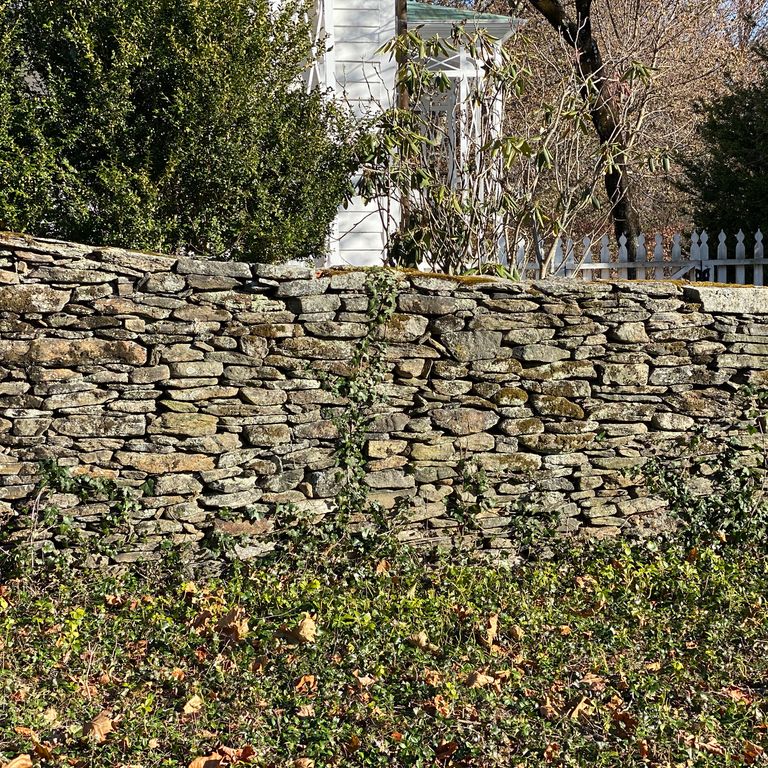 Application image for New England Fieldstone Flats - Wallstone. The image shows this product being used in a landscape wallstone application. The surface finish shown is weathered. The dominant color shown is gray. The color mix creates a warm feeling.