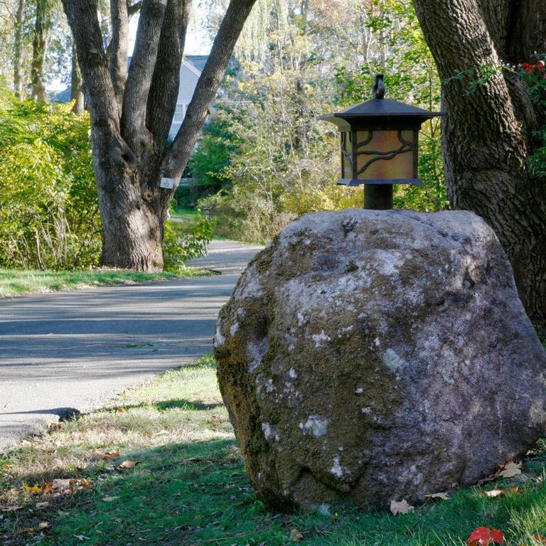 Feature image for New England Fieldstone Boulders & Ledgestone - Fountains & Lights. The image shows this product being used in a garden accents application. The surface finish shown is weathered. The dominant color shown is gray; with black, blue, brown and purple secondaries. Blotched, random and cloudy color patterns.