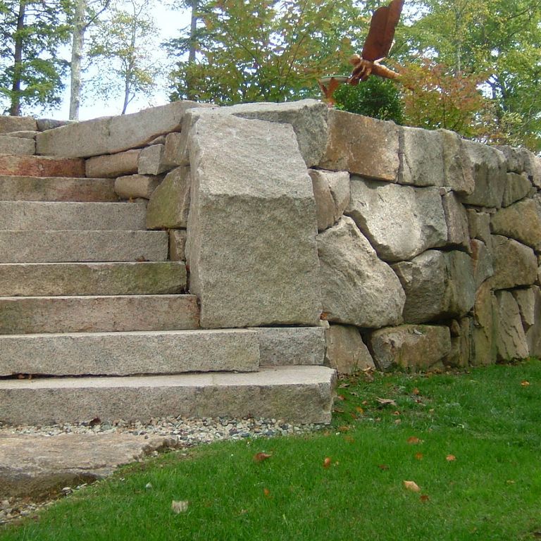 Feature image for Reclaimed Granite Step - Live Edge. The image shows this product being used in a monolithic steps application. The dominant color shown is gray; with beige, brown, green, orange/rust, white and tan secondaries. Fine speckled and blotched color patterns.