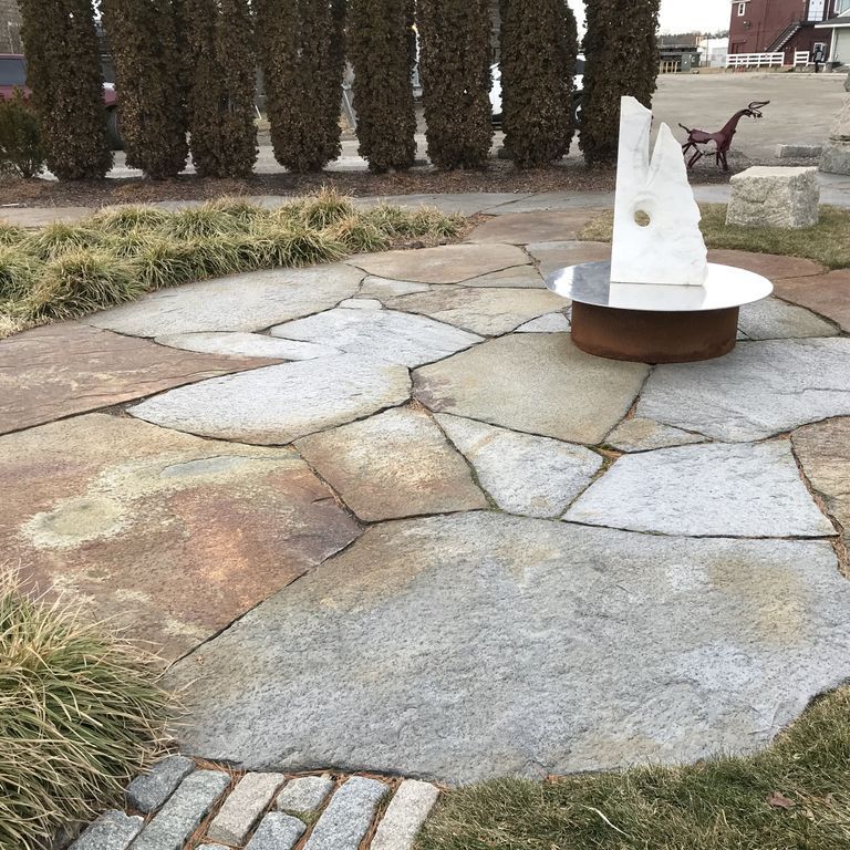 Application image for Goshen Stone - Irregular Flagstone. The image shows this product being used in a patio pavers application. The surface finish shown is split-face with flat plane. Dominant colors shown are brown, gray and tan; with beige, blue, orange/rust and purple secondaries. The color mix creates a warm feeling. Regular and blotched color patterns. Contains lots of mica and mineral inclusions.