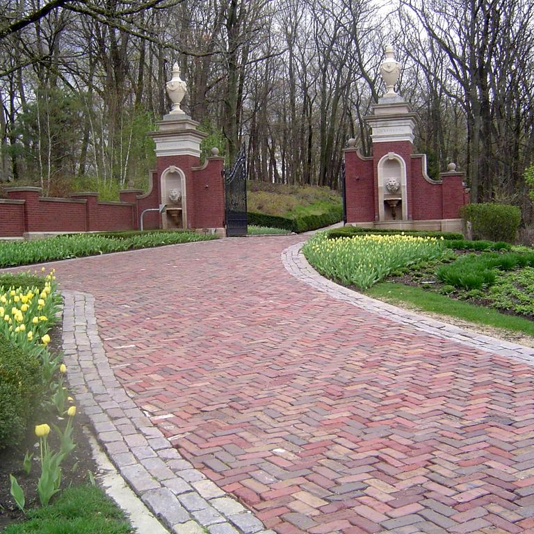 Feature image for Brick - Reclaimed Midwest - Pavers. The image shows this product being used in a driveway pavers application. Dominant colors shown are brown, gray and pink; with beige, blue, orange/rust, purple and tan secondaries. The color mix creates a warm feeling. Regular color pattern.