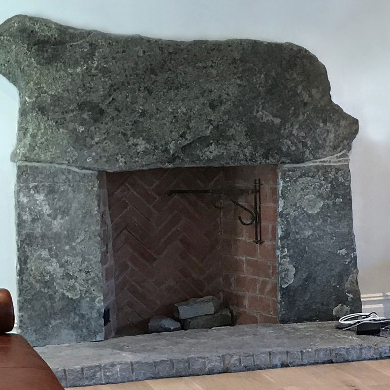 Feature image for Reclaimed Granite Fire Feature - Hearth, Mantel, Surround. The image shows this product being used for fireplace hearth and fireplace surround. The surface finish shown is split-face. The dominant color shown is gray; with black, brown and green secondaries. The color mix creates a cool feeling. Swirled, speckled, blotched and cloudy color patterns.