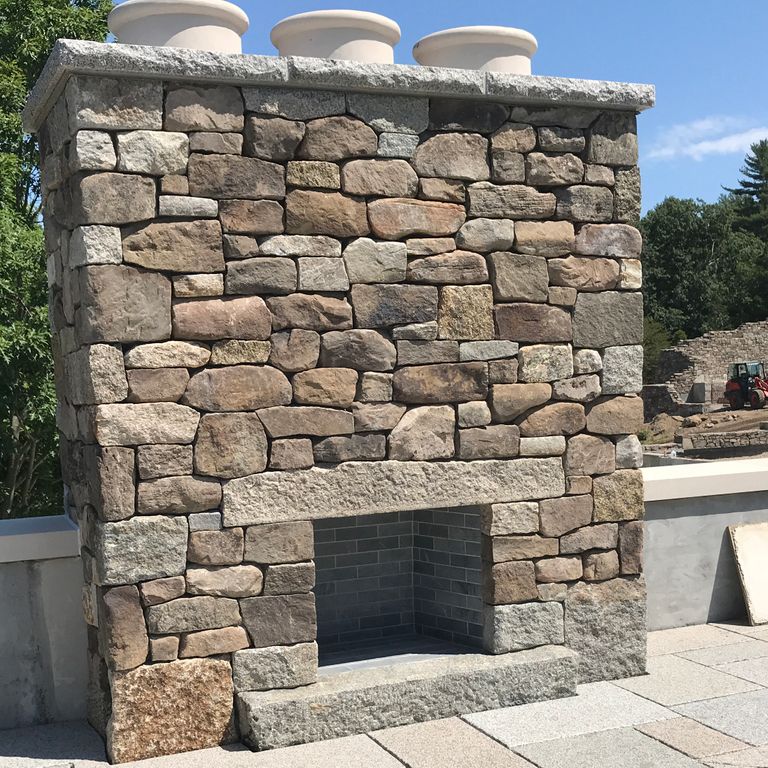 Application image for Reclaimed Granite Fire Feature. The image shows this product being used for fireplace hearth and fireplace surround. This is a building and landscape stone for indoor and outdoor residential applications. Suitable for general use situations. Higher to high on the price spectrum.