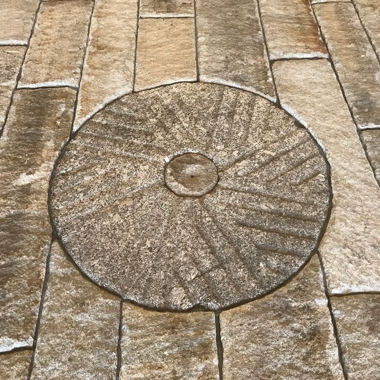 Feature image for Reclaimed Granite - Millstone. The image shows this product being used in a garden accents application. Dominant colors shown are brown and tan; with beige, gray, orange/rust and cream secondaries. The color mix creates a warm feeling. Speckled color pattern.