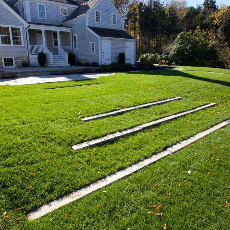 Application image for Reclaimed First Generation Granite Curbstone - Lawn Steps. The image shows this product being used in a monolithic steps application. The surface finish shown is a combination of weathered and worn. The dominant color shown is gray; with a tan secondary. The color mix creates a cool feeling. Regular color pattern.