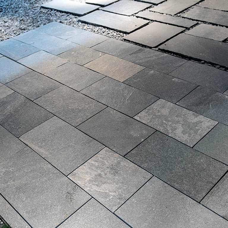 Feature image for Greek Quartzite Slate - Grey - Dimensional Sawn Pavers. The image shows this product being used in a patio pavers application. The dominant color shown is gray; with beige, black, blue, brown, purple and white secondaries. Exhibits 