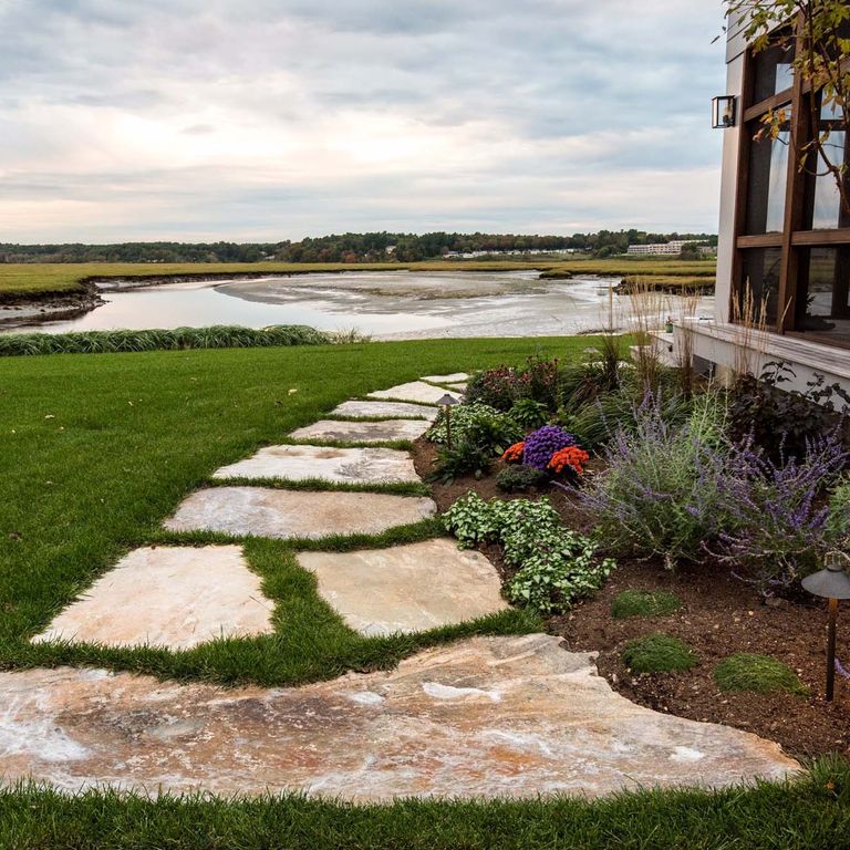 Application image for Granite - Black Mountain - Oversized Irregular Pavers - Natural top. The image shows this product being used in a path pavers application. Dominant colors shown are brown and gray. The color mix creates a warm feeling.
