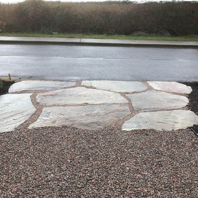 Application image for Granite - Black Mountain - Oversized Irregular Pavers - Natural top. The image shows this product being used in a driveway aprons application. The dominant color shown is gray. The color mix creates a warm feeling.