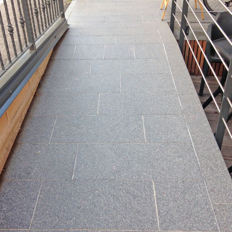 Feature image for Porphyry Worked Surface - Gray Real Dimensional Pavers. The image shows this product being used in a path pavers application. The dominant color shown is gray. The color mix creates a cool feeling. Speckled color pattern.