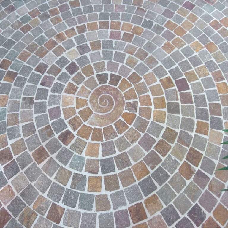 Best close-up image for Porphyry Natural Surface - Mixed Color Cobblestones. The image shows this product being used for driveway pavers and patio pavers. The dominant color shown is gray; with blue, orange/rust, pink, purple, red and tan secondaries. Speckled and cloudy color patterns.
