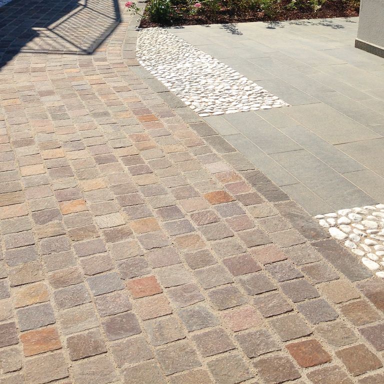 Feature image for Porphyry - Natural Surface - Mixed Color Cobblestones. The image shows this product being used in a path pavers application. Dominant colors shown are beige and tan. The color mix creates a warm feeling. Regular and fine speckled color patterns.