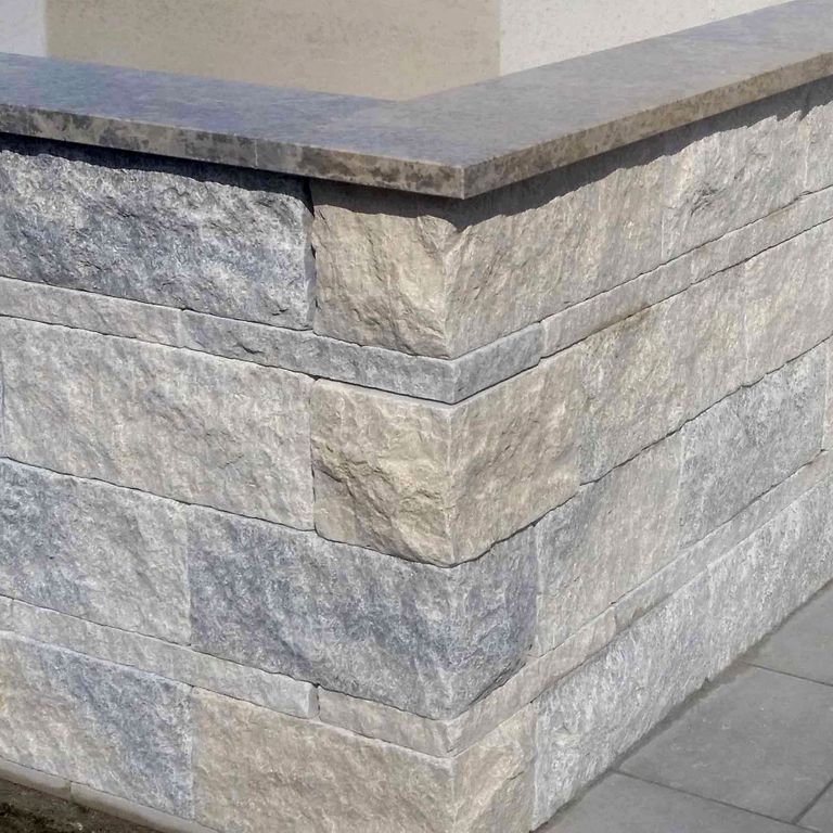 Feature image for Mountain Hard Limestone Mix - Wall Veneer. The image shows this product being used in a full bed veneer application. The dominant color shown is gray; with beige, blue, purple, white and cream secondaries. Exhibits 
