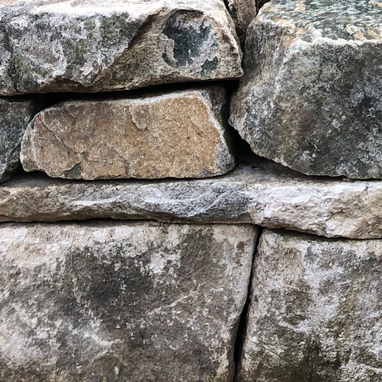 Close-up image for Black Mountain Granite Natural - Wallstone. The surface finishes shown are split-face and split-face with rough plane. The dominant color shown is gray; with beige, black, brown, green, orange/rust, purple, white and tan secondaries. Exhibits 