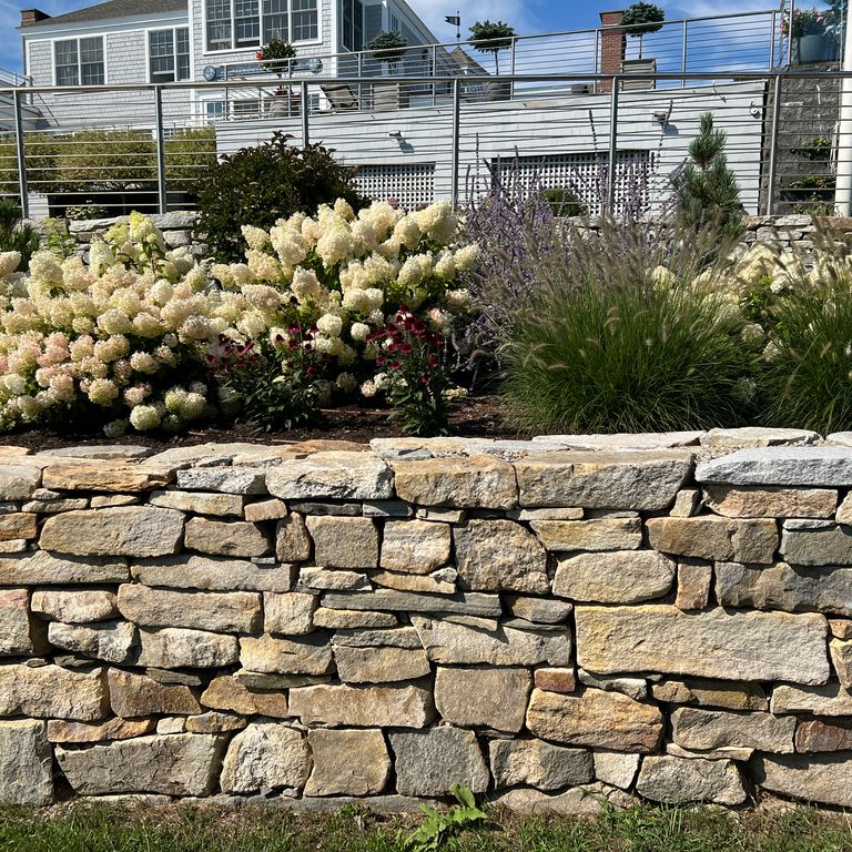Application image for Black Mountain Granite Natural - Wallstone. The image shows this product being used in a landscape wallstone application. Dominant colors shown are brown and tan. The color mix creates a warm feeling.