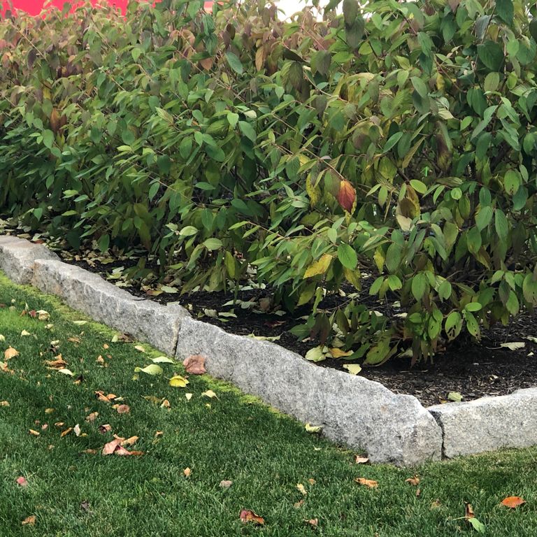 Application image for Granite - Reclaimed - Edging. The image shows this product being used in a landscape curbing & edging application. This is a landscape stone for outdoor commercial and residential applications. Suitable for general use, freeze-thaw conditions, low heat absorption surfaces and low slipperiness surfaces situations. Relatively moderate in price.