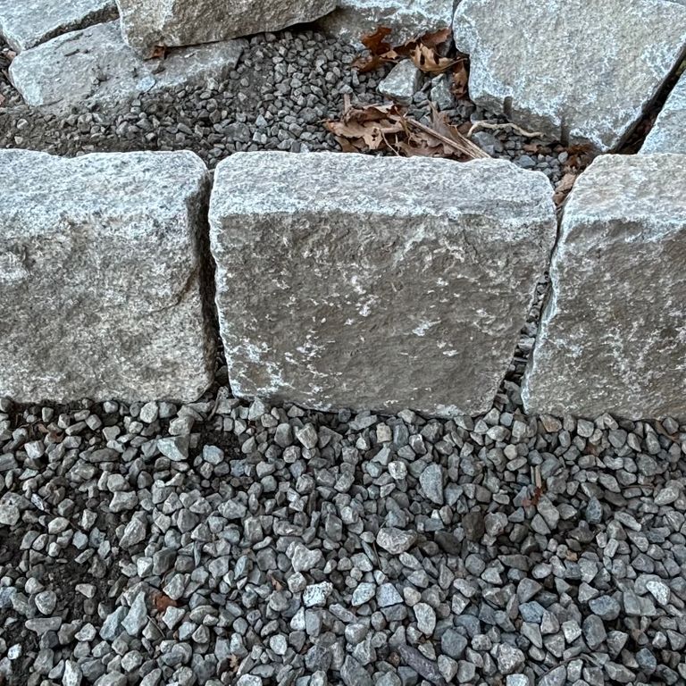 Application image for Granite - Reclaimed New England Cobblestones - Super Jumbo Edging. The image shows this product being used in a landscape curbing & edging application. The dominant color shown is gray. The color mix creates a cool feeling.
