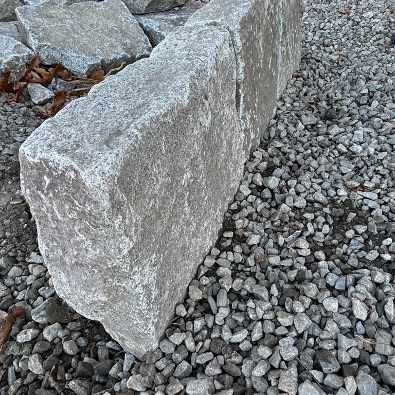Application image for Granite - Reclaimed New England Cobblestones - Super Jumbo Edging. The image shows this product being used in a landscape curbing & edging application. The dominant color shown is gray.