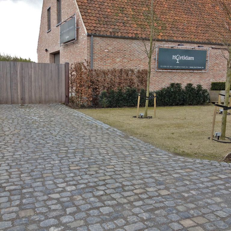 Application image for Reclaimed Belgian Bluestone Cobblestones - Worn Surface. The image shows this product being used in a driveway pavers application. The surface finish shown is . The dominant color shown is gray. The color mix creates a warm feeling.