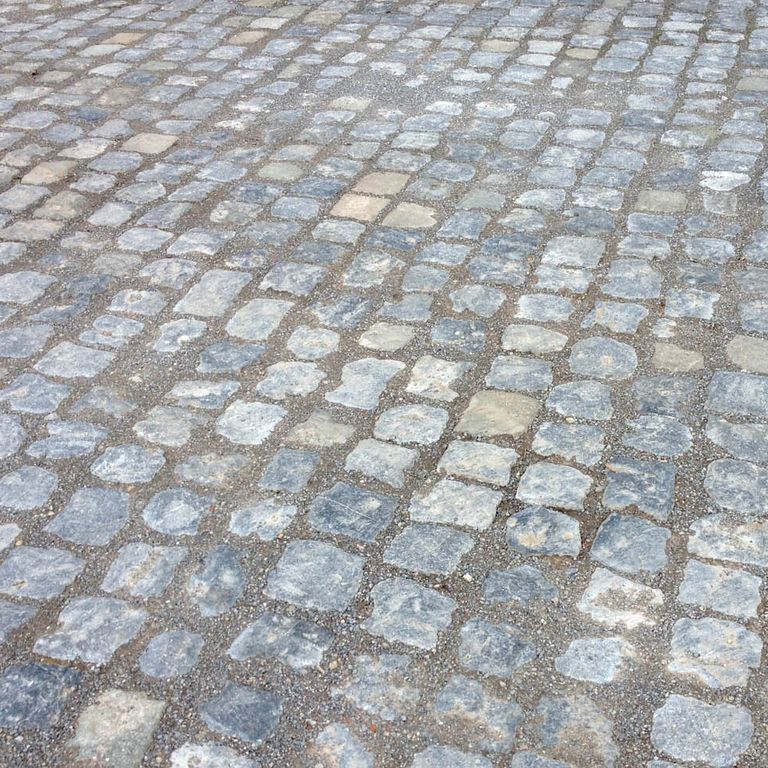 Application image for Reclaimed Belgian Bluestone Cobblestones - Worn Surface. The image shows this product being used in a driveway pavers application. The surface finish shown is . The dominant color shown is gray. The color mix creates a cool feeling.