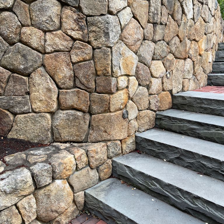 Application image for New England Fieldstone Veneer. The image shows this product being used for full bed veneer and thin veneer. The surface finish shown is natural. Dominant colors shown are brown and tan; with beige, gray, orange/rust, purple and cream secondaries. The color mix creates a warm feeling.