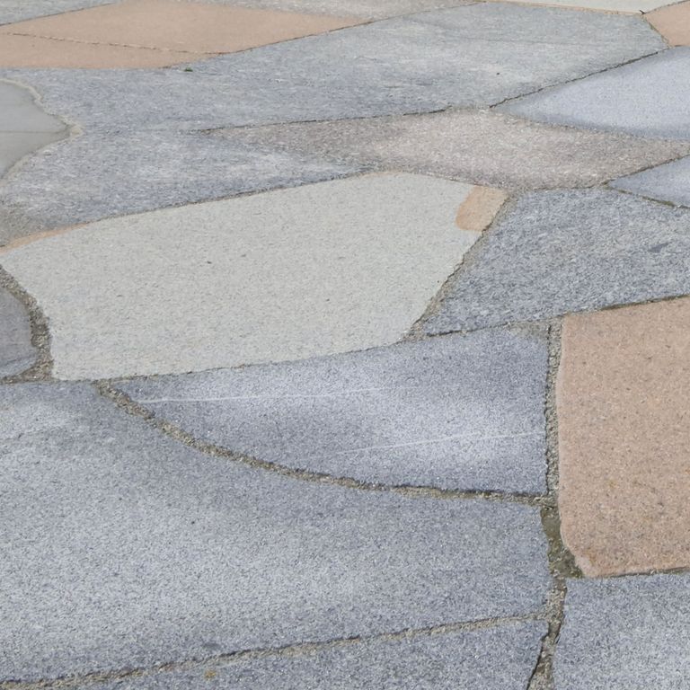 Best close-up image for New England Granite Mix - Live Edge Paver. The image shows this product being used in a patio pavers application. The surface finish shown is flamed. Dominant colors shown are beige, gray and white. Fine speckled, speckled and cloudy color patterns. Contains mineral inclusions.