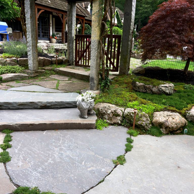 Application image for Bluestone Natural Cleft Full Color Mix - Irregular Pavers - Jumbo. The image shows this product being used in a path pavers application. The surface finish shown is natural cleft. Dominant colors shown are gray, pink and white. The color mix creates a cool feeling.