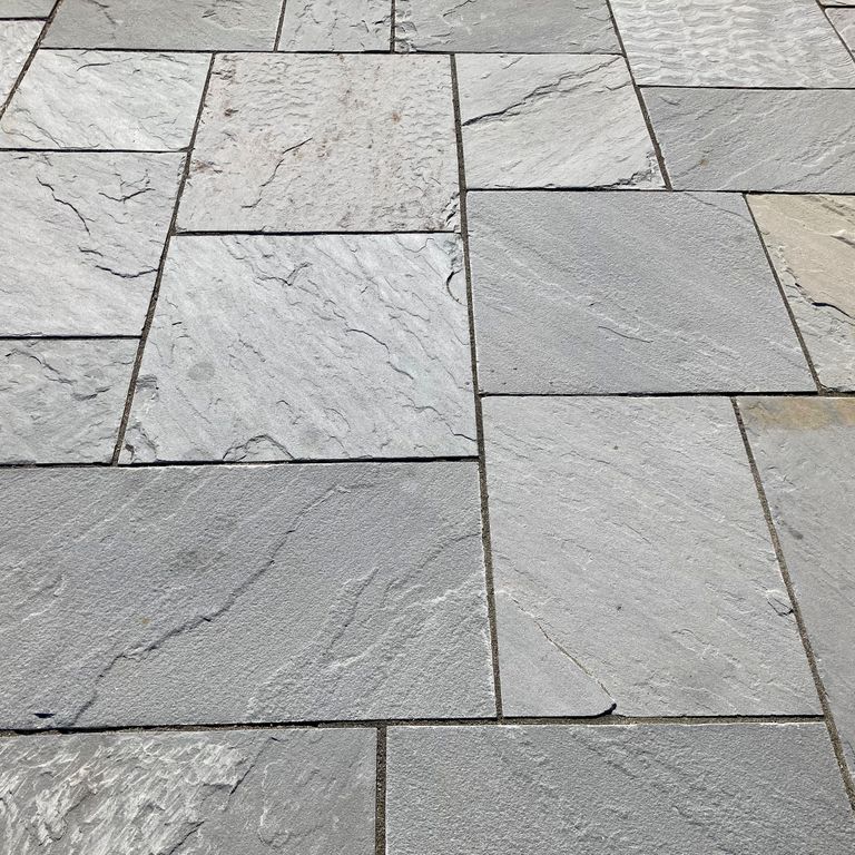 Application image for Bluestone Natural Cleft Blue/Gray - Dimensional Cut Pavers. The image shows this product being used in a patio pavers application. The surface finish shown is natural cleft. The dominant color shown is gray; with a beige secondary. The color mix creates a cool feeling.