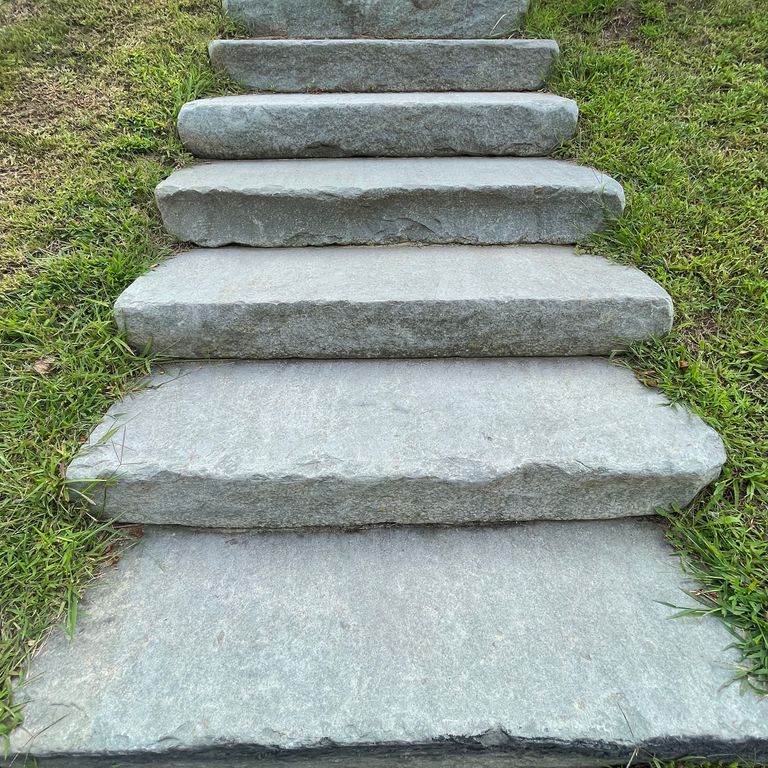 Best close-up image for Bluestone Flamed Surface Blue/Gray - Tumbled Pavers. The image shows this product being used in a monolithic steps application. The surface finish shown is tumbled. The dominant color shown is gray; with blue and white secondaries. The color mix creates a cool feeling. Solid and cloudy color patterns.