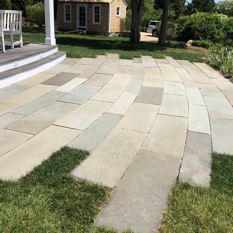 Application image for Clear Color Mix Bluestone - Natural Cleft Dimensional Cut Pavers. The image shows this product being used in a patio pavers application. Dominant colors shown are beige, gray and cream; with white and tan secondaries. Exhibits 