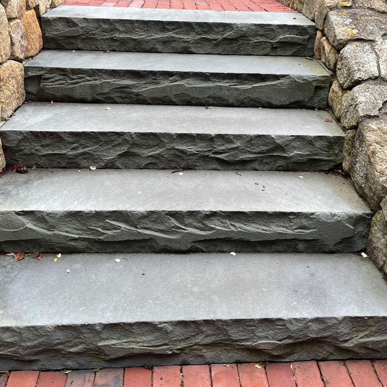 Best close-up image for Bluestone Flamed Surface Blue/Gray - Monolithic Steps. The image shows this product being used in a monolithic steps application. The surface finish shown is a combination of flamed and rockfaced. The dominant color shown is gray; with a white secondary. The color mix creates a cool feeling. Solid color pattern.