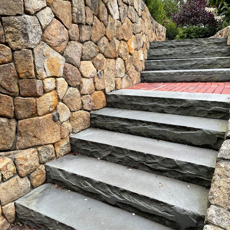 Application image for Bluestone Flamed Surface Blue/Gray - Monolithic Steps. The image shows this product being used in a monolithic steps application. The surface finish shown is a combination of flamed and rockfaced. The dominant color shown is gray; with blue and white secondaries. The color mix creates a cool feeling. Solid color pattern.