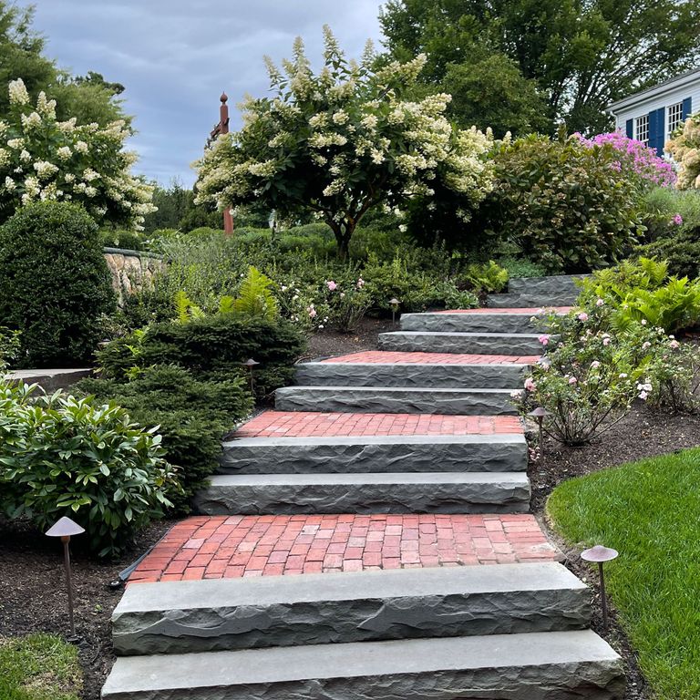 Application image for Bluestone Flamed Surface Blue/Gray - Monolithic Steps. The image shows this product being used in a monolithic steps application. The surface finish shown is a combination of flamed and rockfaced. The dominant color shown is gray; with a blue secondary. The color mix creates a cool feeling. Solid color pattern.
