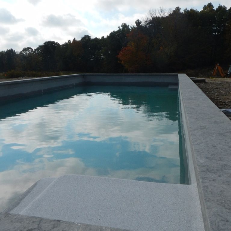 Feature image for Limestone- Portuguese Dawn Haze - Pool Coping. The image shows this product being used for pool coping and pool deck pavers. The dominant color shown is gray. Exhibits 