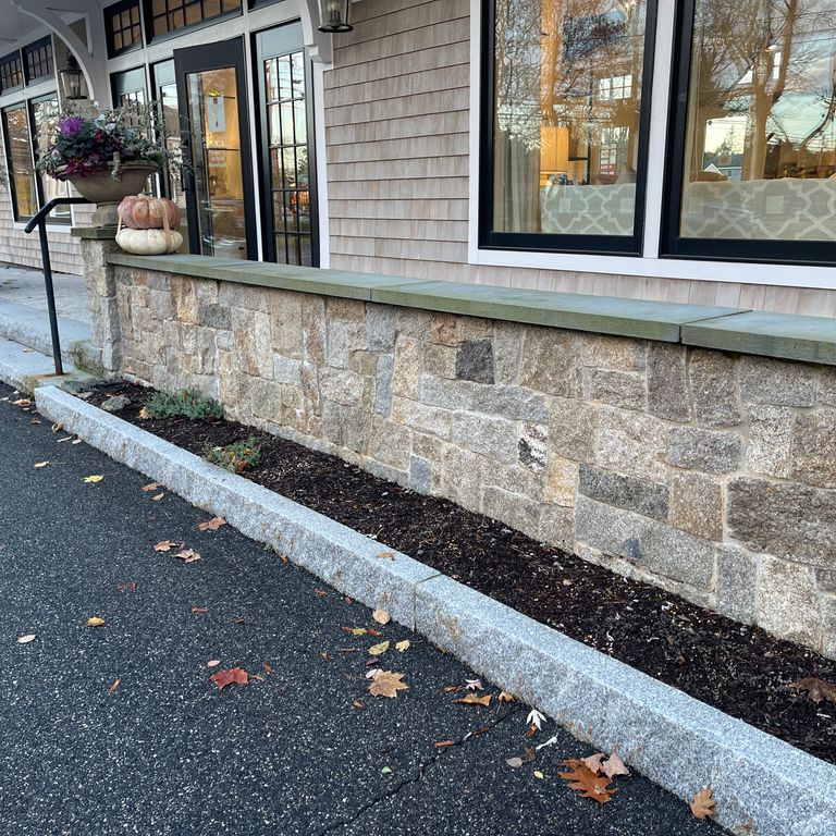 Application image for Cape Neddick Clear Granite - Full Bed Veneer. The image shows this product being used for landscape wallstone and full bed veneer. The dominant color shown is gray.