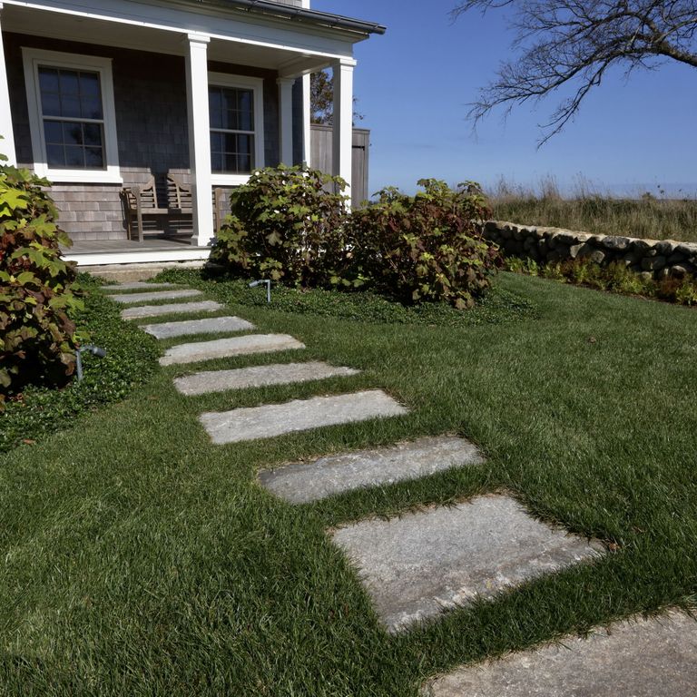 Application image for Reclaimed First Generation Granite Curbstone - Steppers. The image shows this product being used in a path pavers application. The surface finish shown is a combination of weathered and worn. The dominant color shown is gray. The color mix creates a cool feeling.