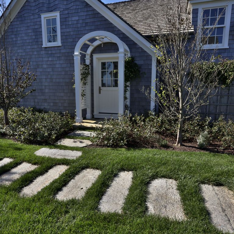 Application image for Reclaimed First Generation Granite Curbstone - Steppers. The image shows this product being used in a path pavers application. The surface finish shown is a combination of weathered and worn. The dominant color shown is gray; with beige, purple, white and tan secondaries. The color mix creates a warm feeling.