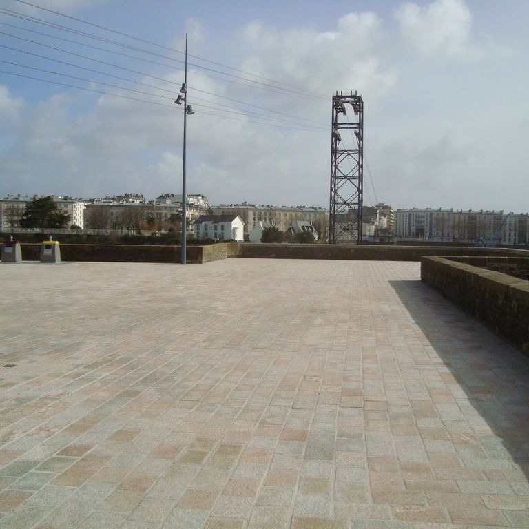 Feature image for Granite - Masterpiece Yellow - Pavers. The image shows this product being used in a public area application. Dominant colors shown are gray and tan; with brown, green and orange/rust secondaries. The color mix creates a warm feeling. Speckled color pattern. Contains some mica and mineral inclusions.
