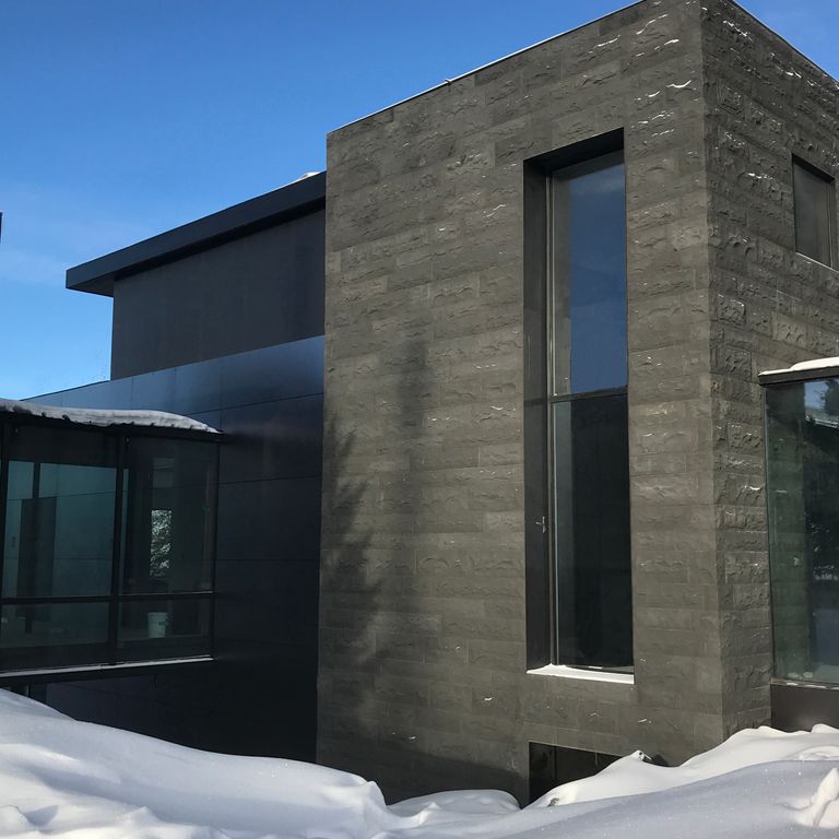 Feature image for Basalt - Ankar Gray - Split Veneer. The image shows this product being used in a full bed veneer application. Dominant colors shown are green and gray; with a brown secondary. Exhibits 