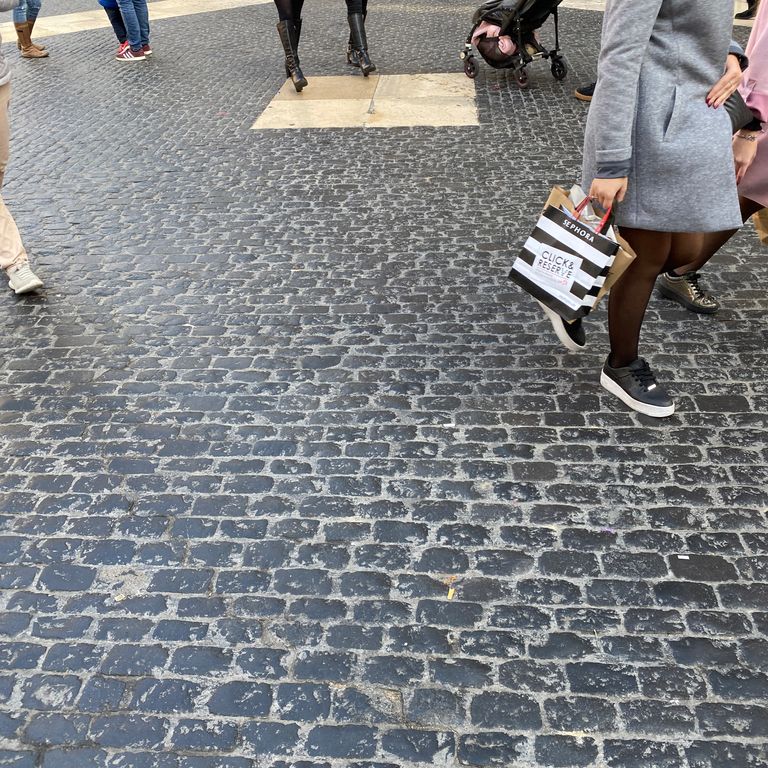 Feature image for Basalt - Ankar Black - Cobblestones. The image shows this product being used for patio pavers and public area. The dominant color shown is gray; with black and blue secondaries. The color mix creates a cool feeling. Solid color pattern.