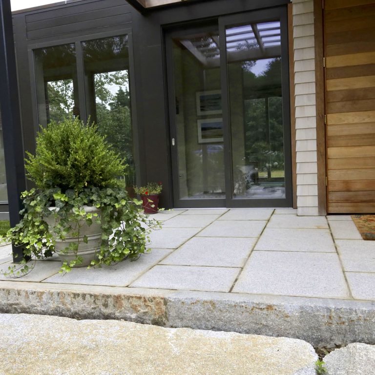 Application image for Cape Neddick Granite Clear - Dimensional Cut Pavers. The image shows this product being used in a patio pavers application. The surface finish shown is a combination of flamed and weathered. The dominant color shown is gray; with a white secondary. The color mix creates a warm feeling. Fine speckled color pattern.