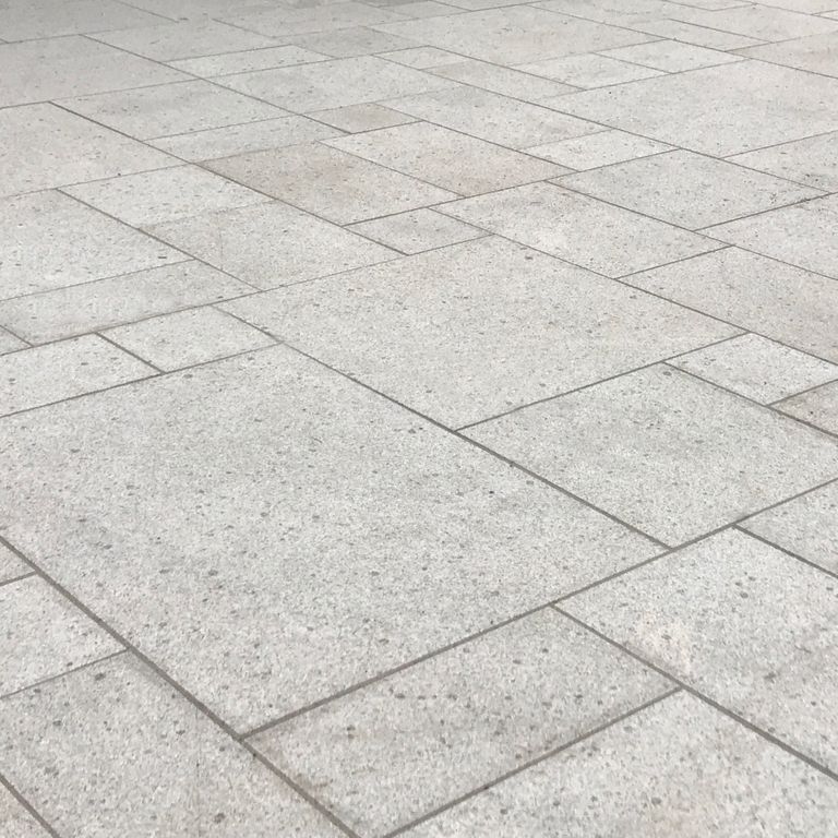 Application image for Granite - Cape Neddick Clear - Dimensional Cut Pavers. The image shows this product being used in a patio pavers application. The surface finish shown is flamed. The dominant color shown is gray; with beige, white and cream secondaries. The color mix creates a cool feeling. Fine speckled color pattern.